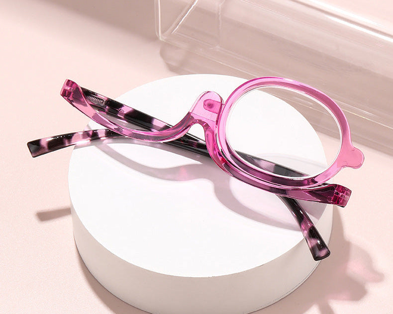 Pink and black tortoiseshell eyeglasses on a white surface with a light pink background